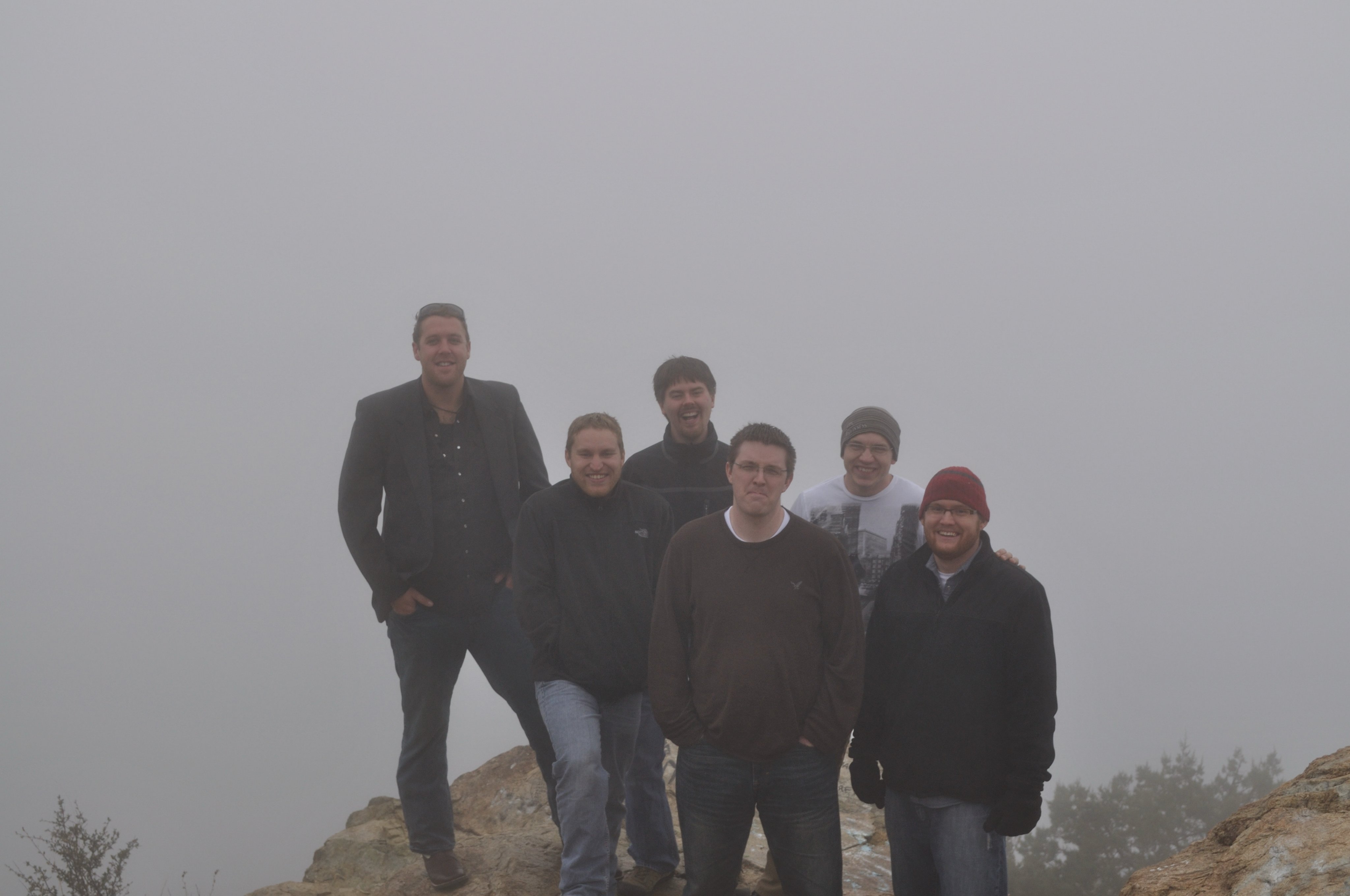 Six people standing together outdoors in the fog